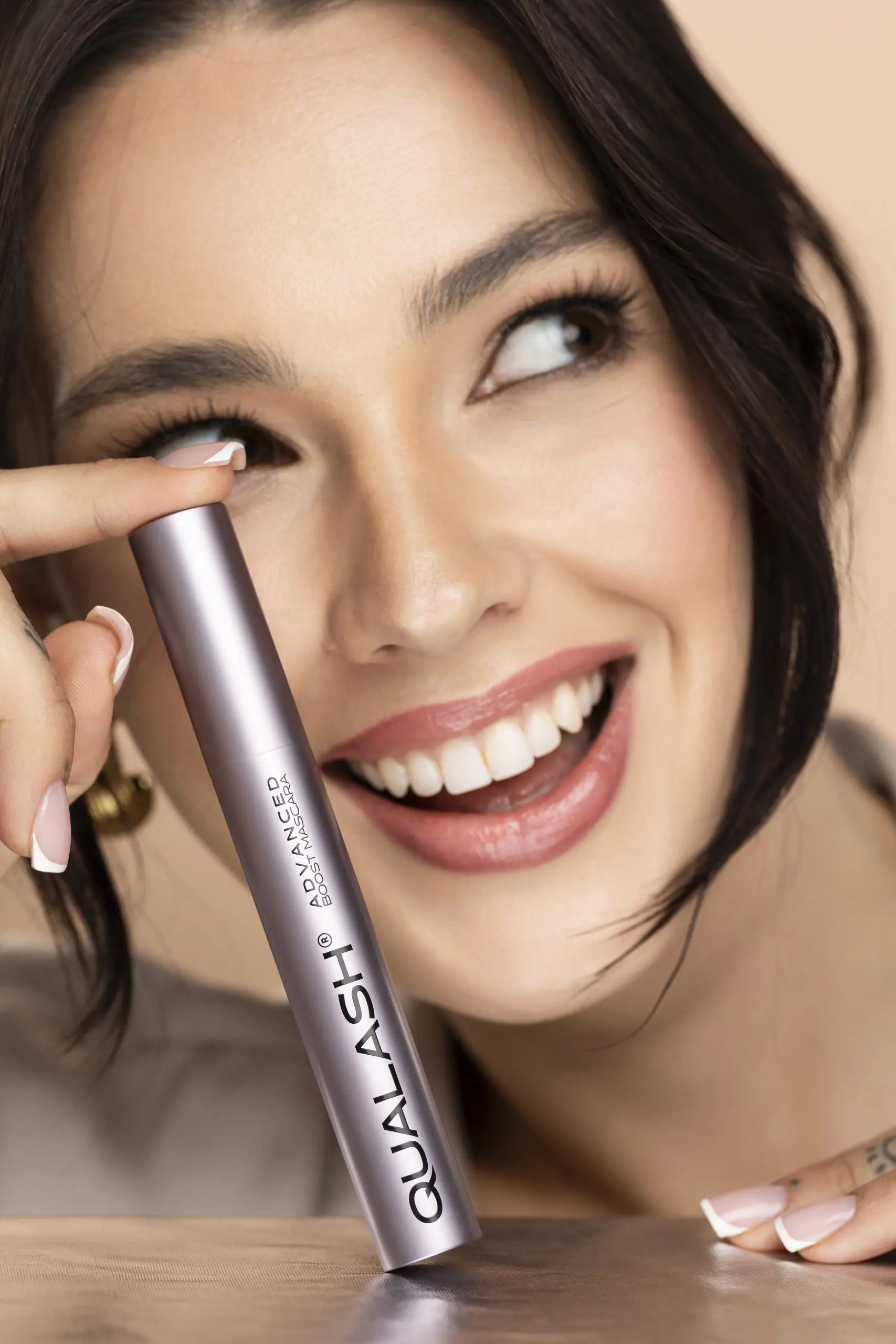 Mulher a aplicar QUALASH Advanced Mascara Volume Max nas pestanas superiores com pincel de precisão – Passo 1